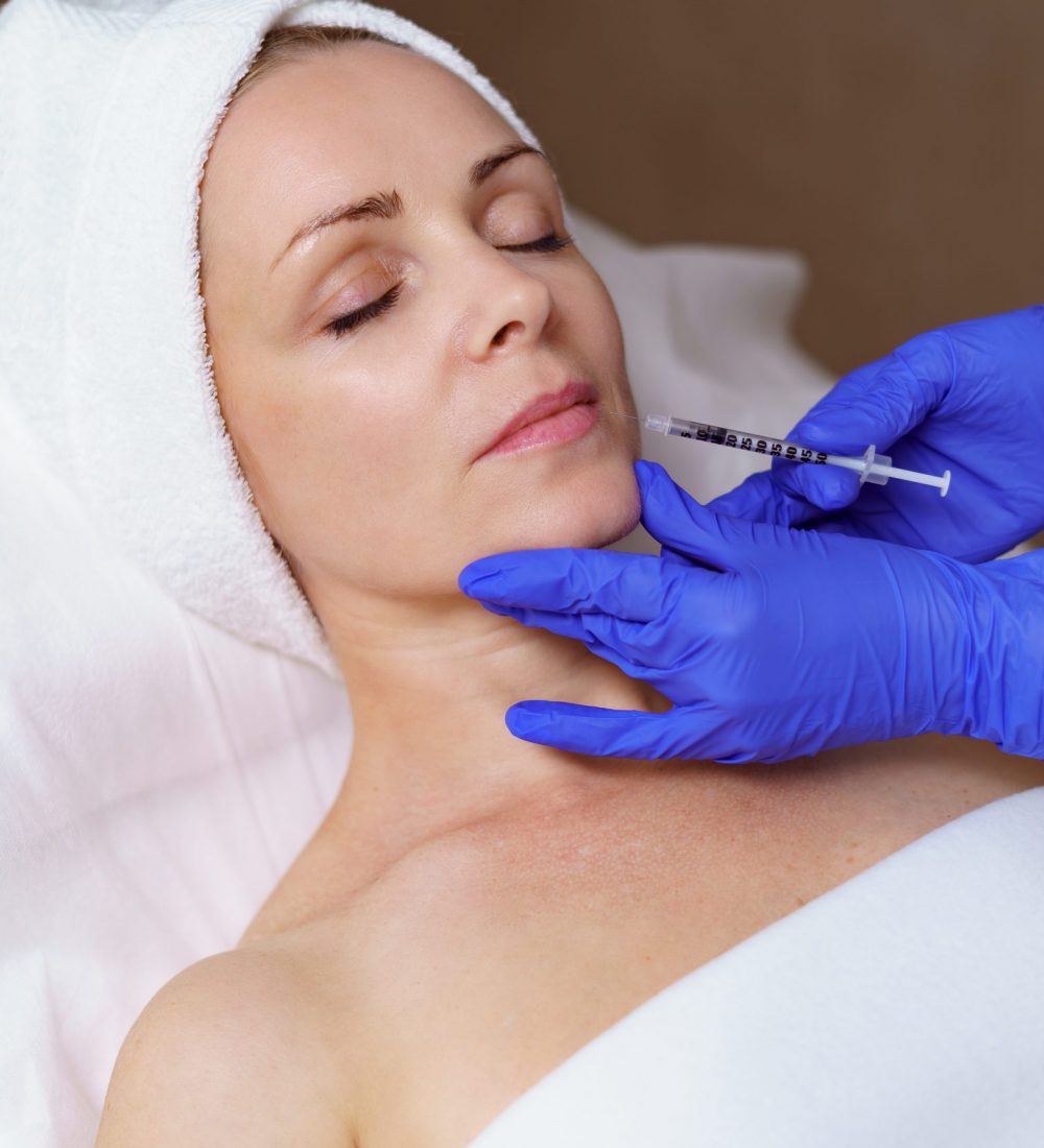 The doctor cosmetologist makes the Rejuvenating facial injections procedure for tightening and smoothing wrinkles on the face skin of a adult woman in a beauty salon