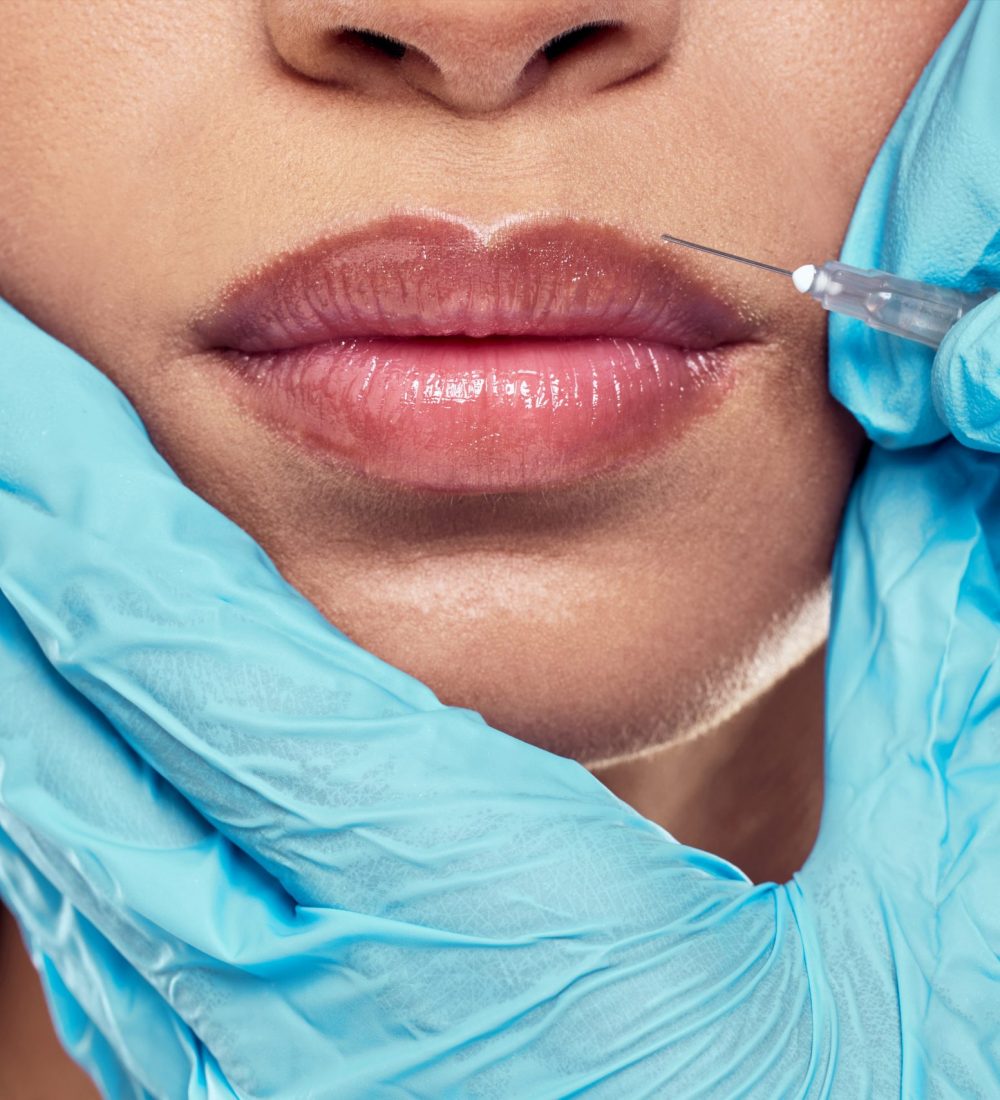 Shot of a woman having her lips injected with filler against a studio background.